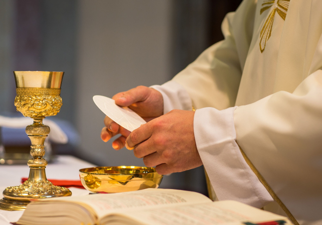 close up photo of priests hands holding the body of Christ