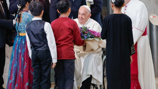 Pope Francis receives a bouquet of flowers from a group of children