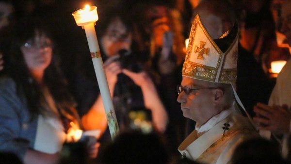 Pope Leo XIV carries a candle as he arrives to celebrate the Easter Vigil